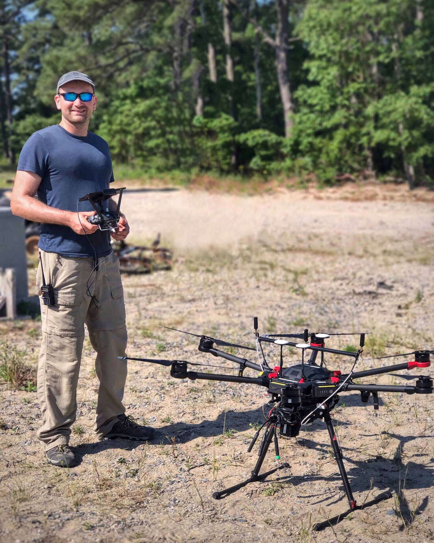 Man preparing to fly a drone in a green field for wind turbine inspections.